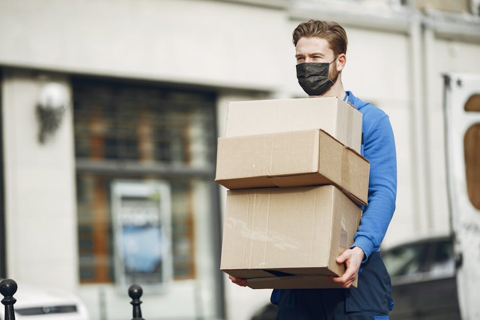 Courier in a blue uniform delivers multiple packages on a city street during the day.