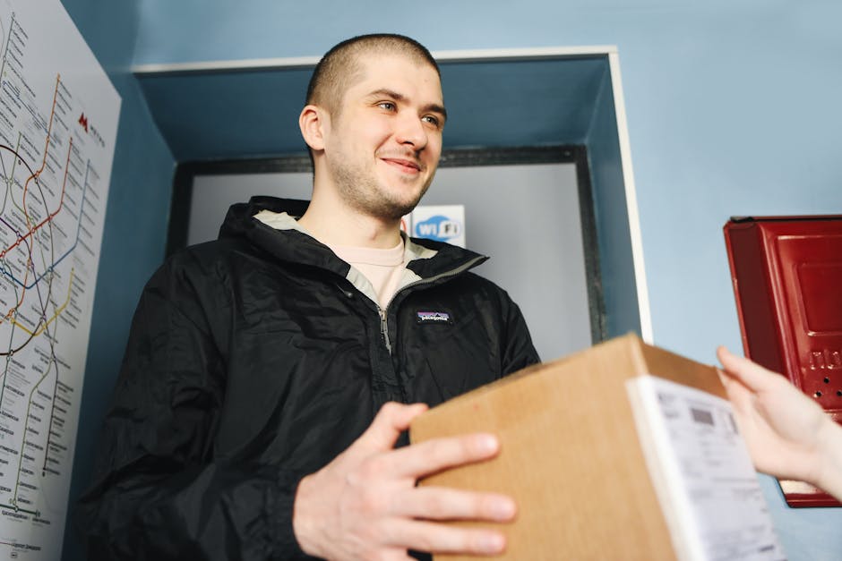 Smiling delivery person hands over a cardboard box indoors, conveying a friendly service.
